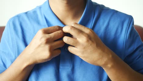 man adjusting his blue polo shirt collar