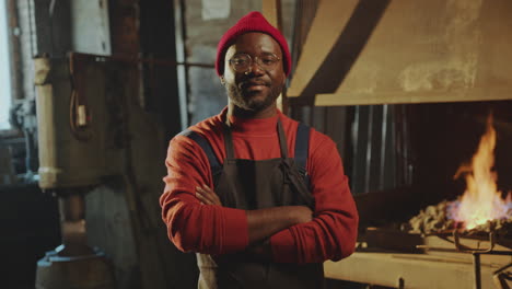 portrait of smiling african american blacksmith in workshop