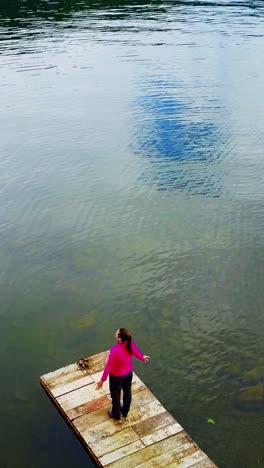 woman on a dock, enjoying the peaceful lake view