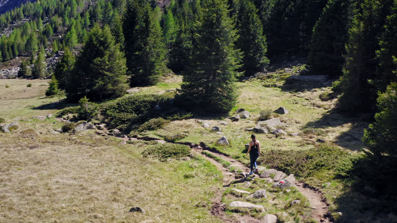 trekker femenino caminando por la pista de montaña