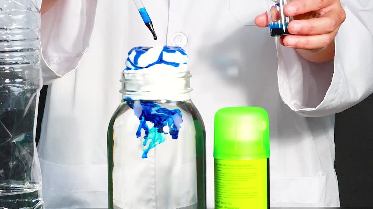 un científico demuestra una reacción química usando crema de afeitar, tinte y una pipeta en un entorno de laboratorio