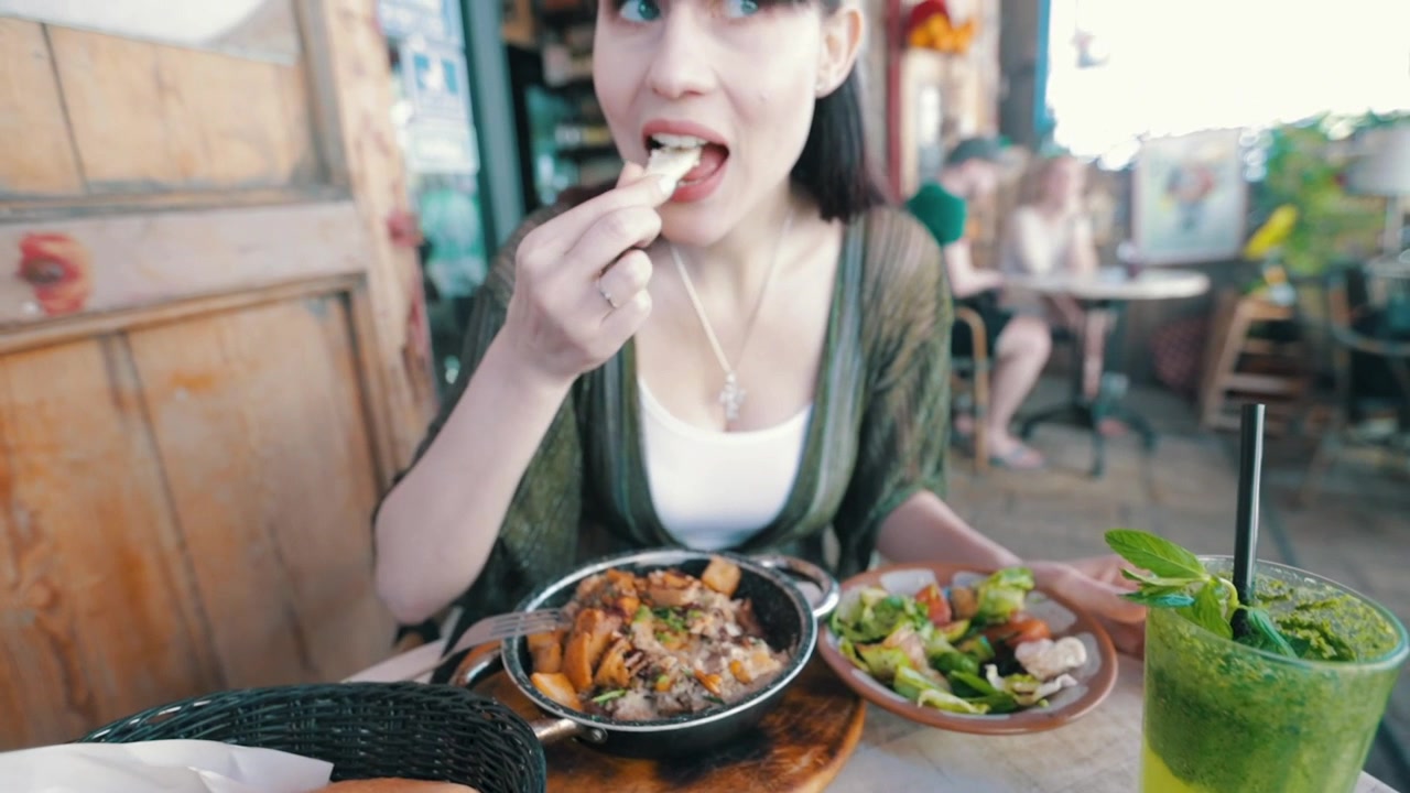 Gadis merobek roti pita dan mencocol hummus - Restoran Israel di Tel-Aviv.