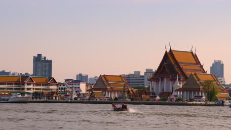 boats moving along a river by city buildings