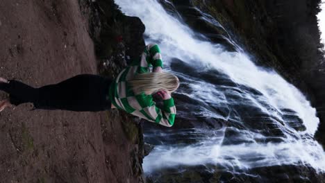 una dama rubia caminando hacia la cascada powerscourt.