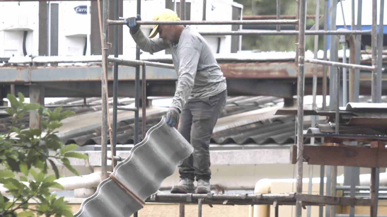 Construction worker on scaffolding installing roof tiles