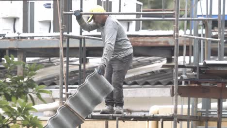 construction worker on scaffolding installing roof tiles