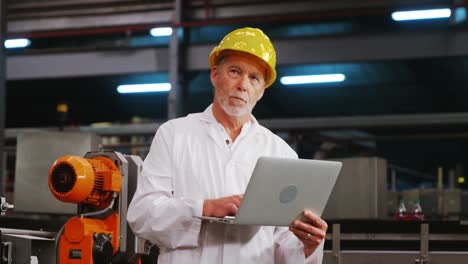 engineer using laptop in bottle factory