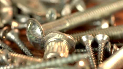 the bunch of steel screws on wooden table. screw production, heap of metal details, close up shot