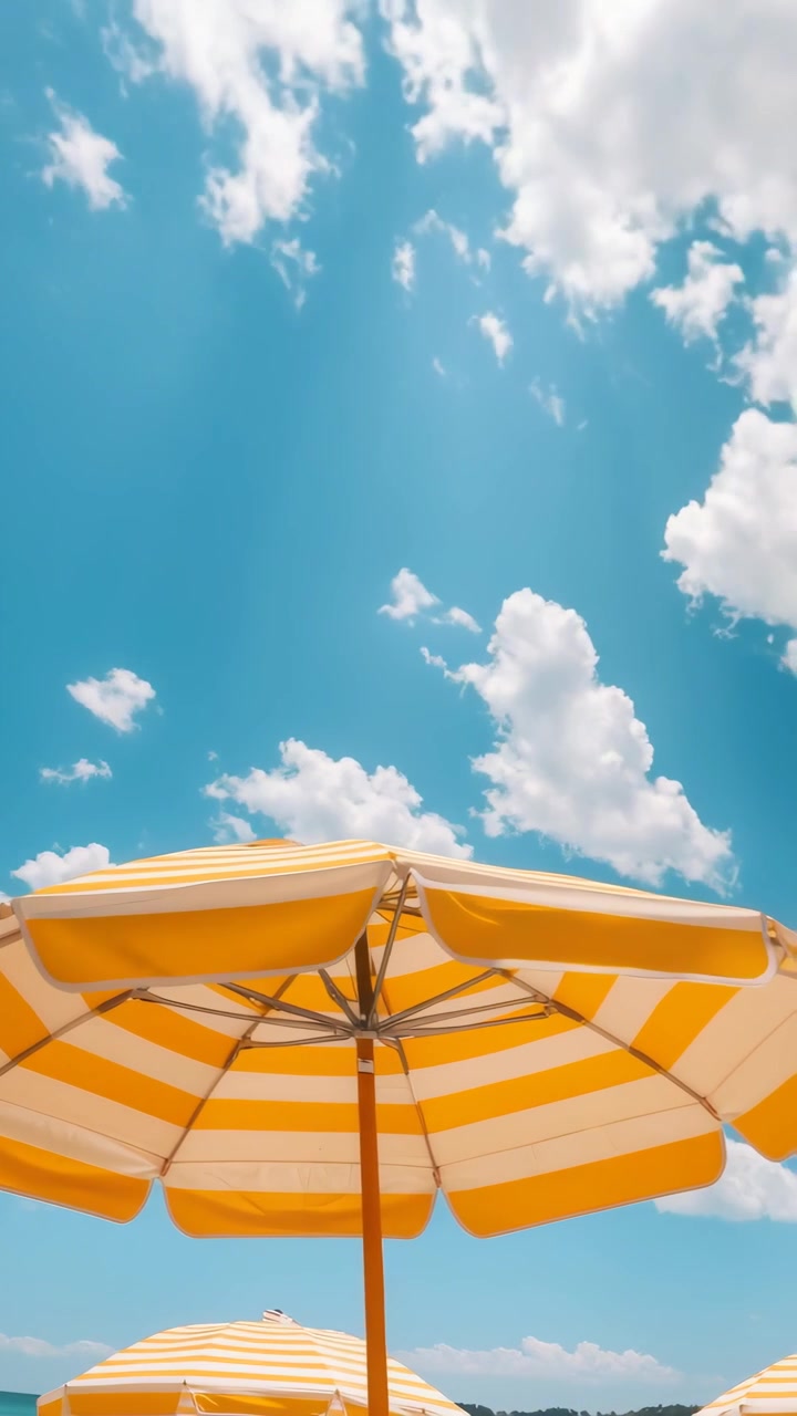 Giornata di sole con ombrelloni da spiaggia a righe e nuvole in movimento.