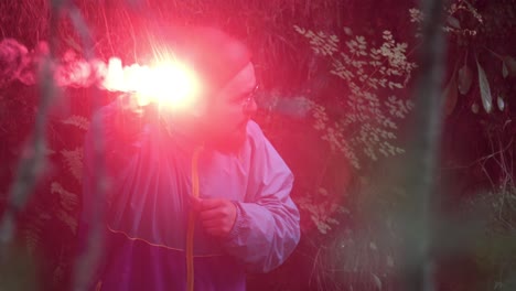 man with red flare in forest at night