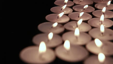 Animation of burning document over lit tea light candles on black background