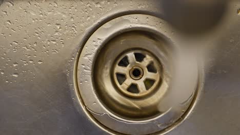 close-up of a stainless steel sink drain with water drops