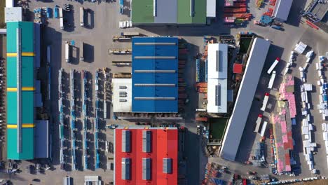 trucks with semi-trailers stand on the parking lot of the logistics park with loading hub and wait for load and unload goods at warehouse ramps at sunset