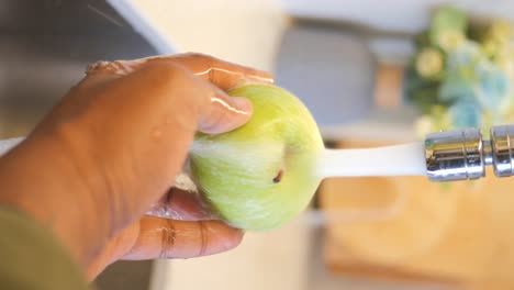 washing green apple under faucet