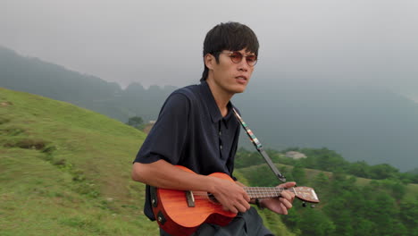 young asian musician playing the ukulele