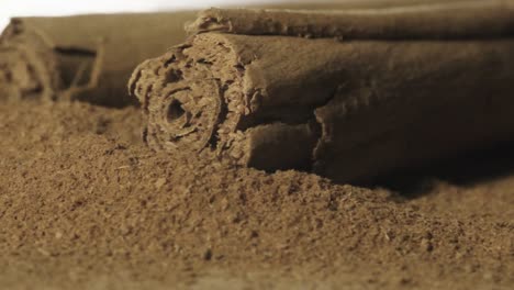 Cinnamom-stick-falls-on-Brown-cinnamom-powder-in-Slow-motion,-Macro-shot