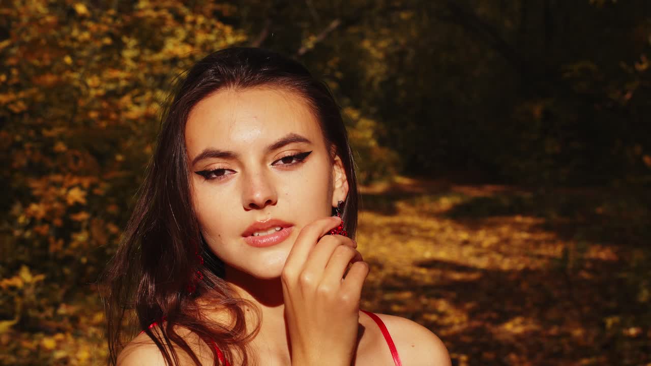 A Captivating Portrait in Autumn: A Woman in Red Elegantly Poses Amidst the Vibrant Fall Foliage, Showcasing Natural Beauty and Grace
