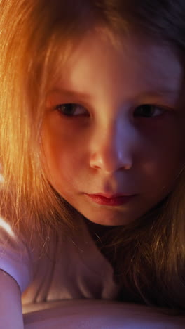 depressed little girl with straight hair embraces large white pillow sitting alone on bed with dimly lit profile in bedroom in evening closeup slow motion