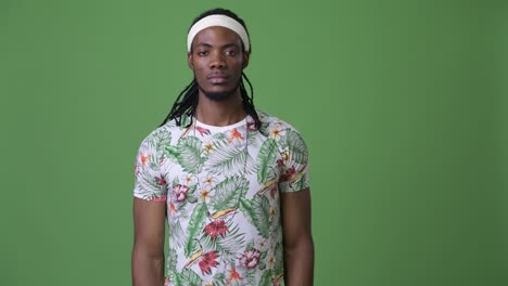young handsome african man with dreadlocks against green background