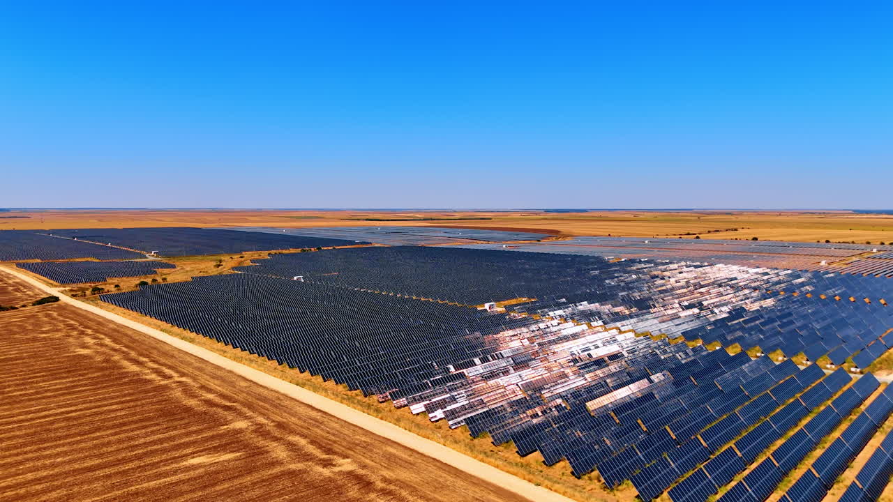 Solar farm field under clear blue sky. Vast solar panels stretch across the landscape, capturing sunlight on a sunny day in a rural area