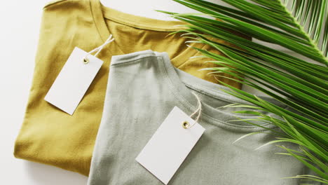 video de primer plano de camisetas verdes y mostaza plegadas con etiquetas en fondo blanco