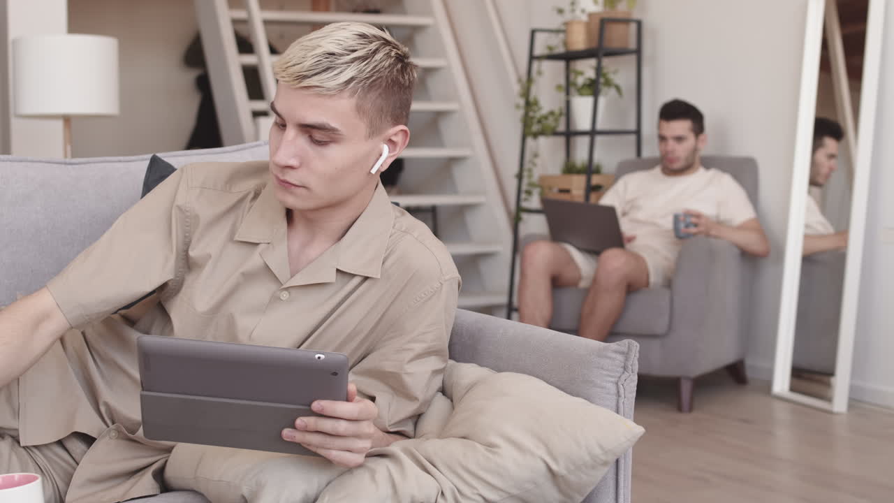 Two Young Men Using Gadgets at Home