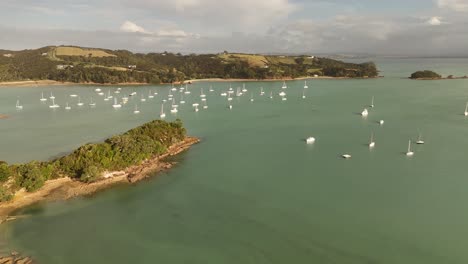birds eye view of sailboats and yachts floating on silent turquoise waters of shelly beach in the surfdale area of waiheke island, new zealand.