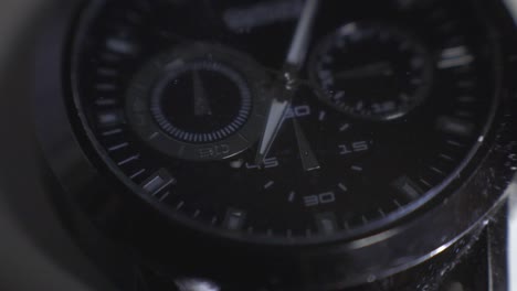 light reflecting on the glass and steel frame of a black wristwatch - close up