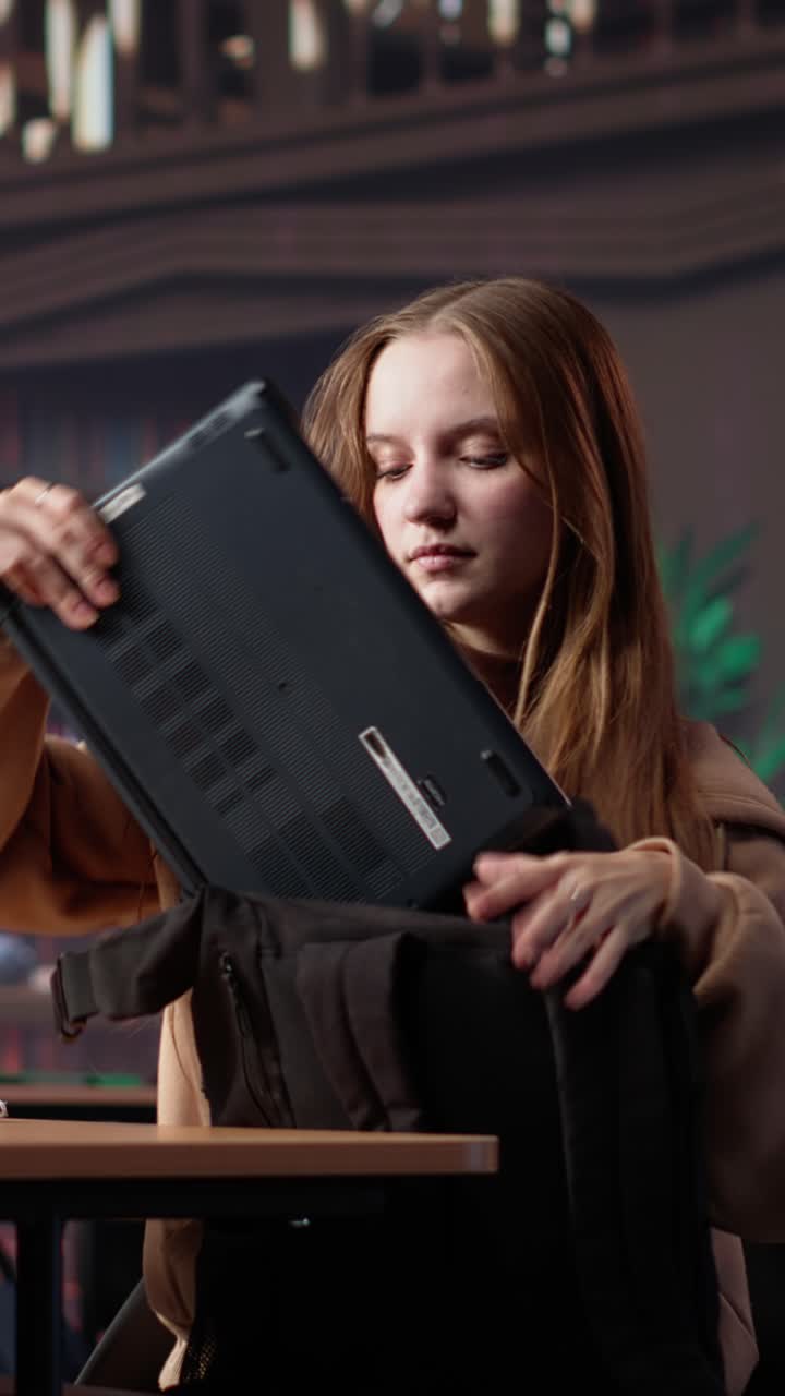 Vertical video focused girl arriving at university library and opening textbook to write notes