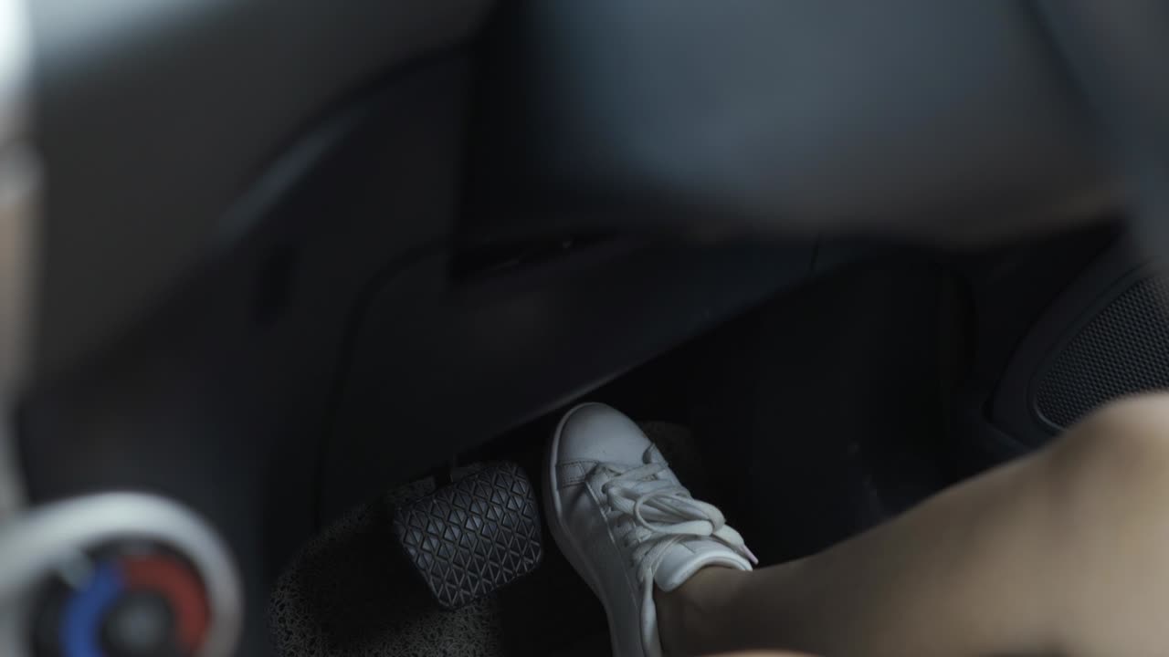 Women driving and stepping on accelerator and brakes in automatic car.