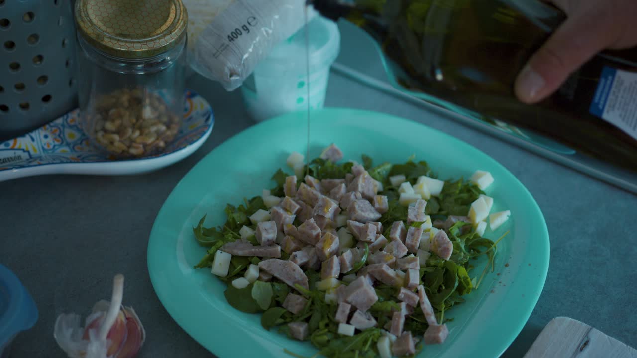 añadiendo aceite de oliva a una ensalada con salchicha en rodajas
