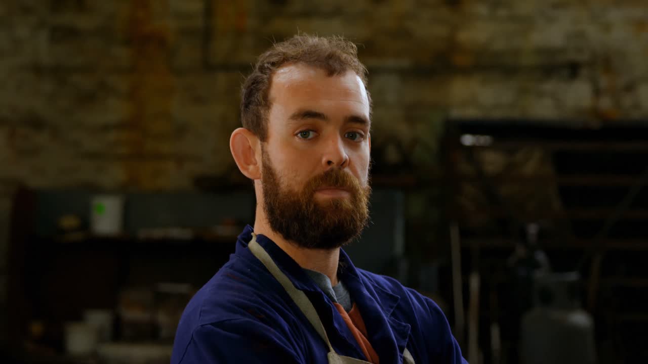 metaalsmid die met gekruiste armen in werkplaats 4k staat