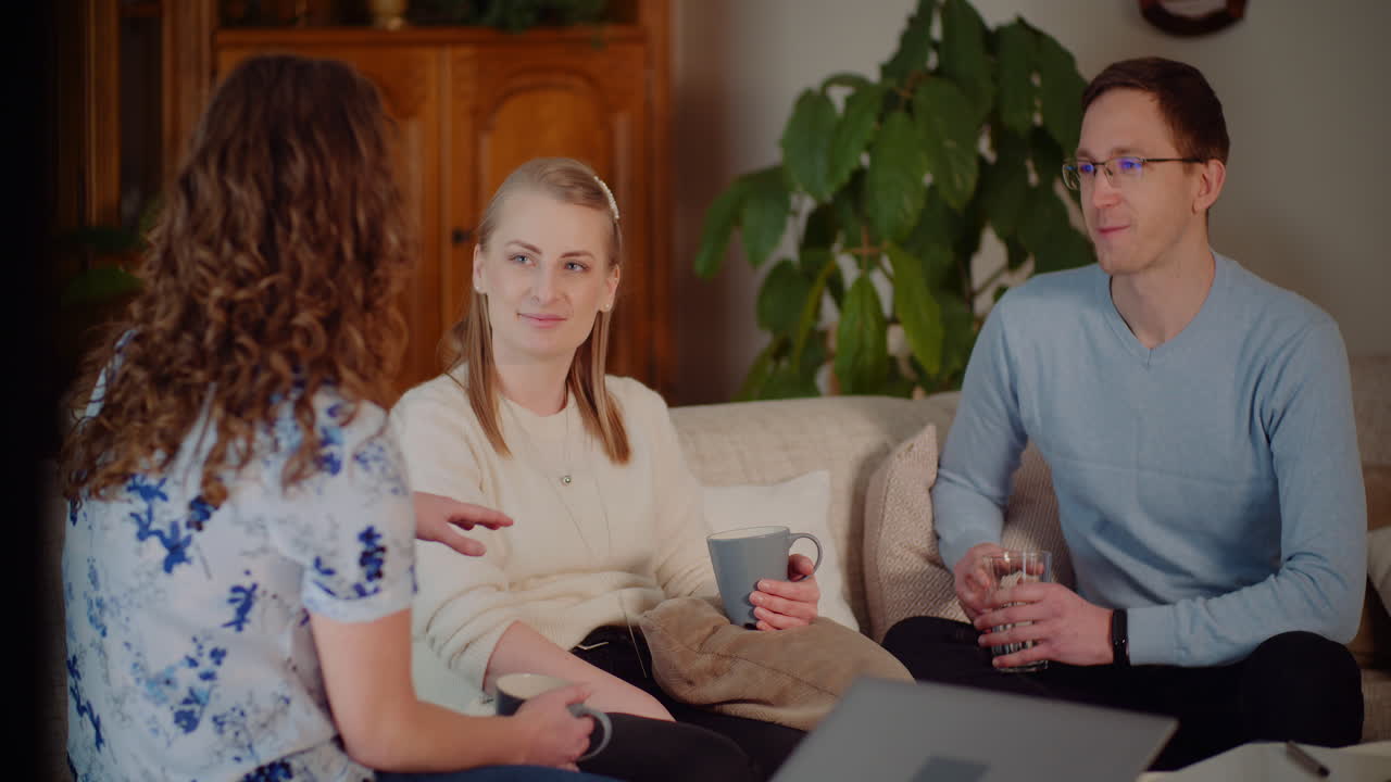 Tre venner, der slapper af og taler på en sofa i en stue