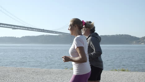 caucasian couple jogging along sea, talking and smiling