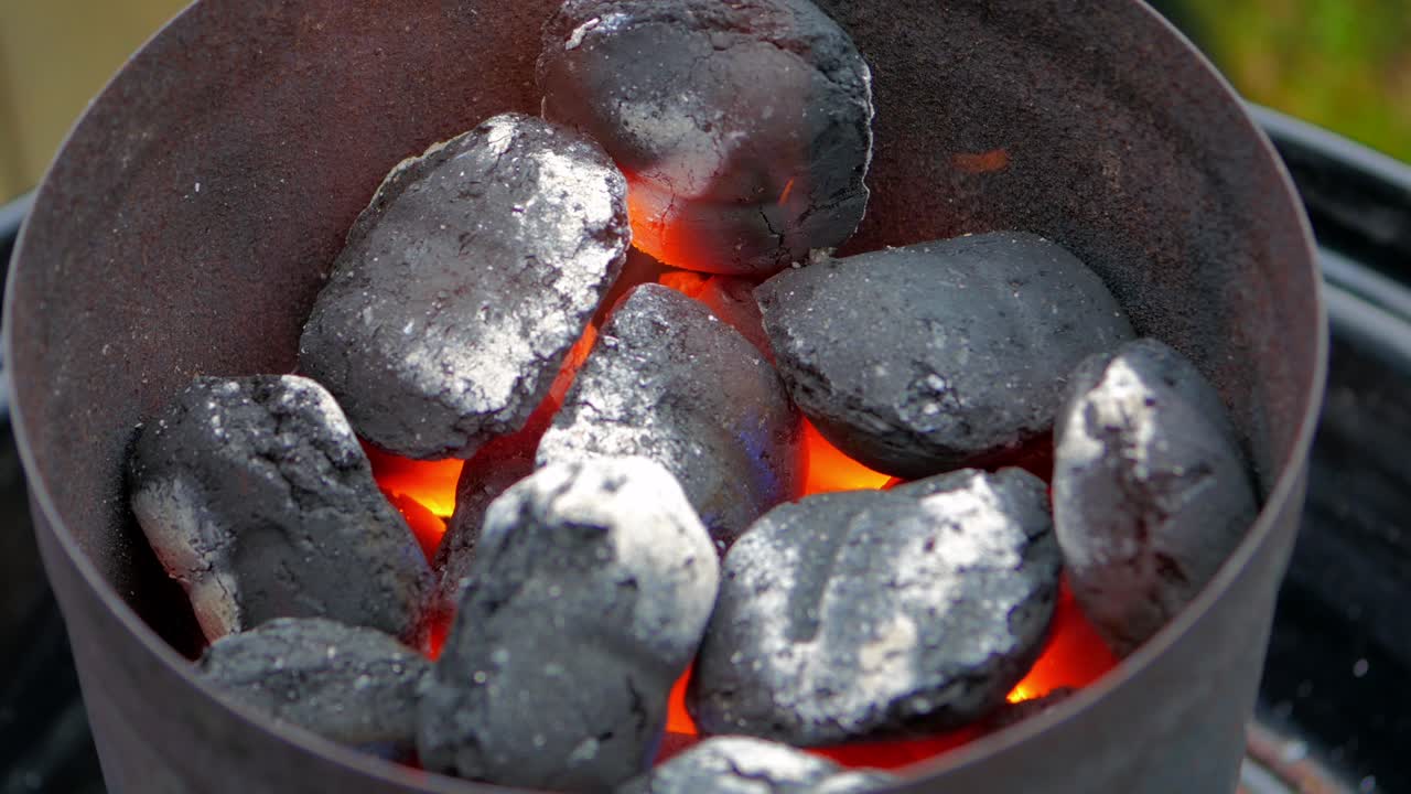 Charcoal chimney filled up and lit up. Flames and sparks fly all over in this brilliant 4K footage.