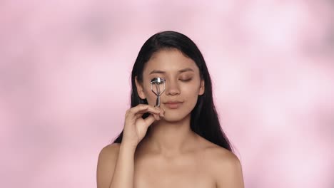 mujer aplicando rizador de pestañas