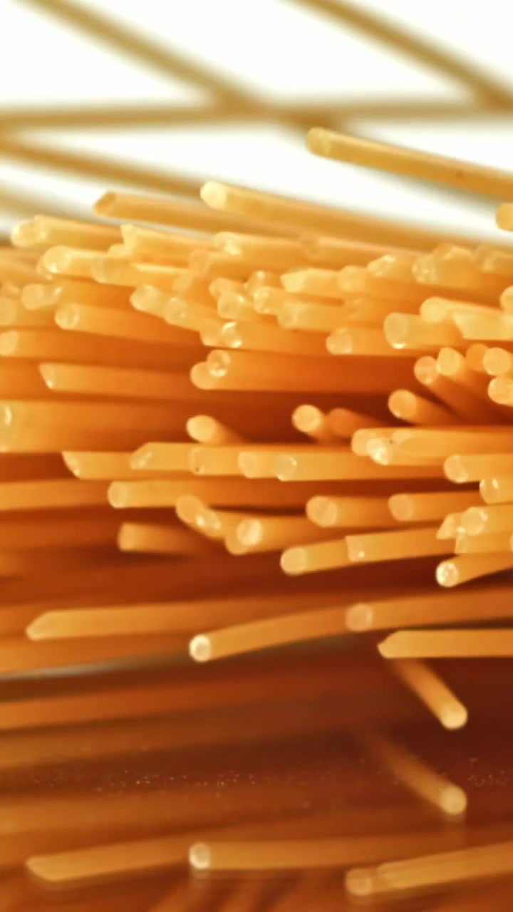 Primo piano di spaghetti crudi che cadono su una superficie riflettente