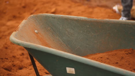 spade shoveling soil into wheelbarrow