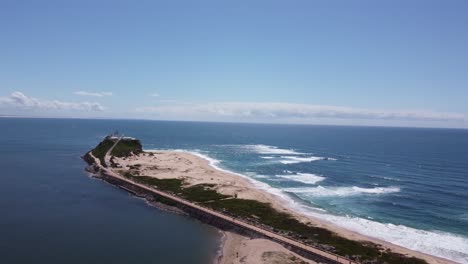 Aerial-view-of-a-peninsula-with-lighthouse-and-sandy-beach