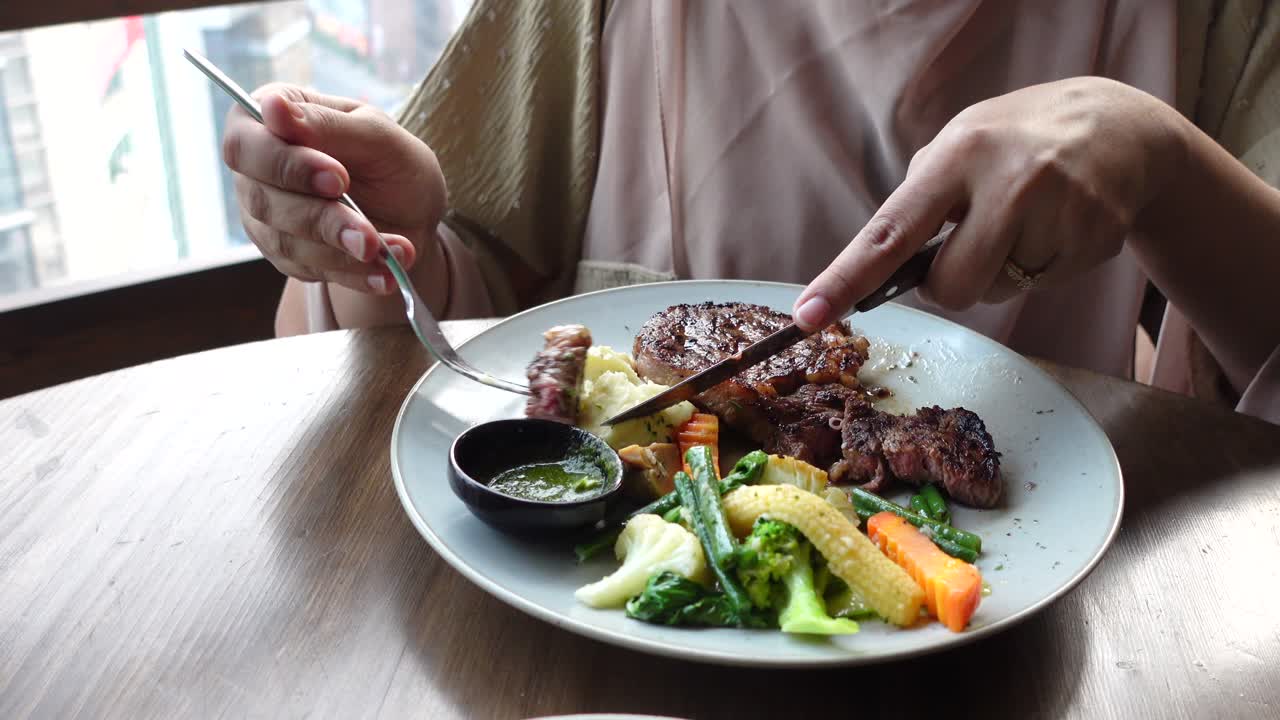 mujer comiendo una cena de bistec en un restaurante
