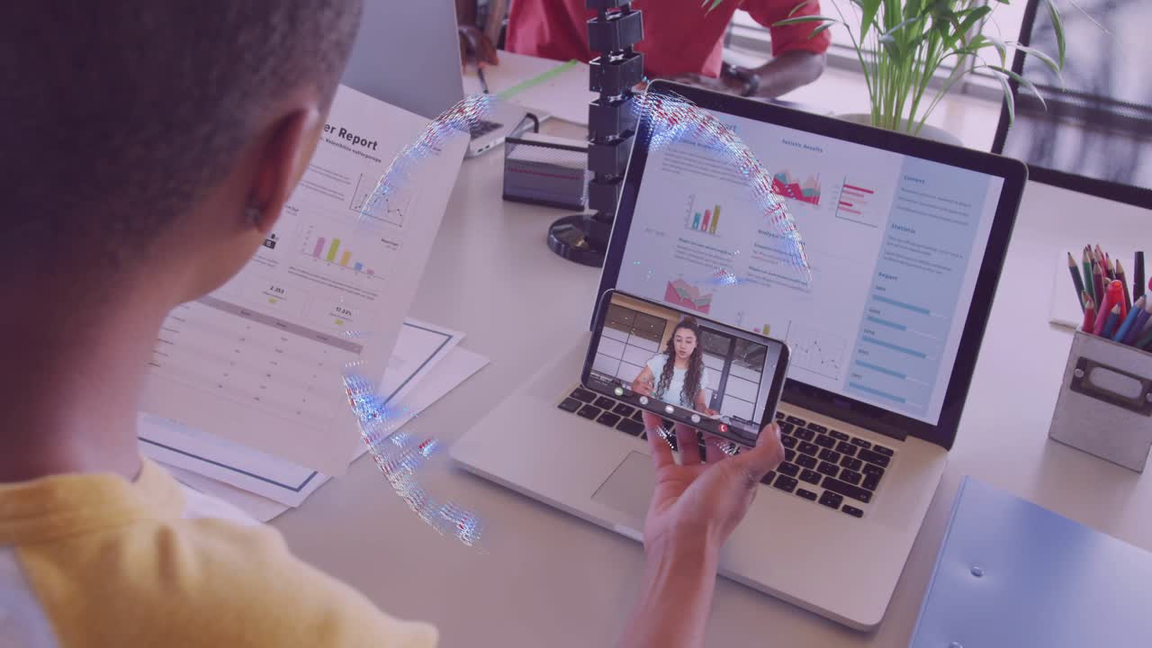 Office worker raising smartphone above laptop projecting globe hologram for business collaboration