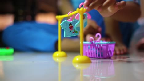 la mano del niño toma la ropa que ha sido lavada en la lavadora de juguetes y luego la cuelga en una percha