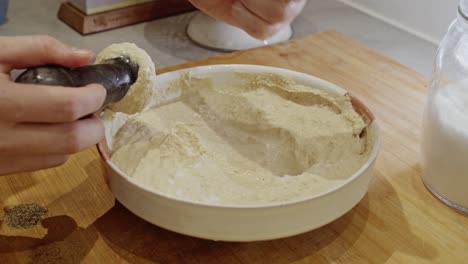 Hand-mashing-chickpeas-into-hummus-on-wooden-table-in-the-kitchen