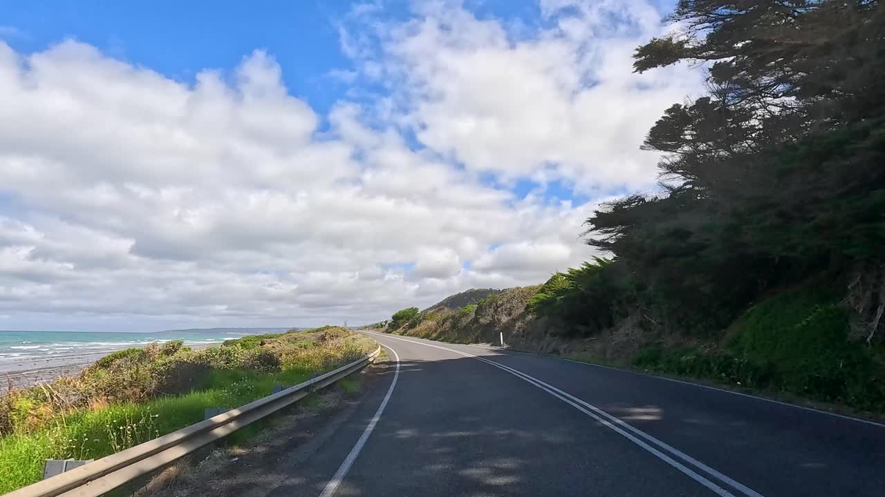 A 15-second video captures a drive along the Great Ocean Road, showcasing coastal views, lush greenery, and a clear blue sky