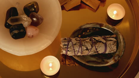 close up of sage and candles on a golden crystal smudge tray