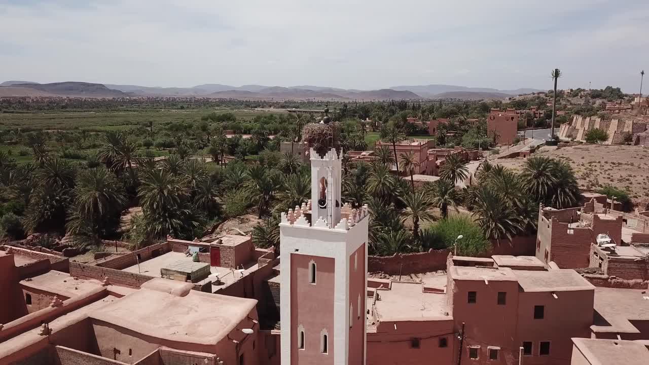 Ripresa cinematografica con drone di un minareto di moschea tradizionale marocchina con un grande nido di cicogne, situato all'interno di un antico ksar in mattoni di fango a Ouarzazate.