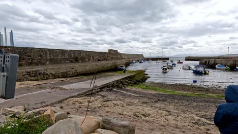 person fishing near boats at dysart beach