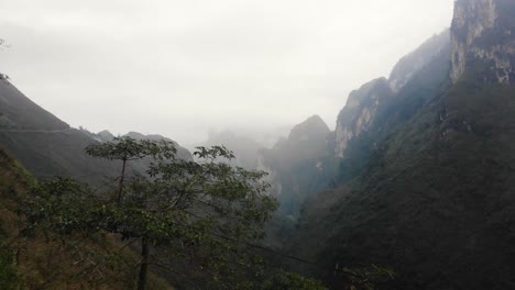 aerial view of ha giang valley with mist covered mountains in the distant. follow shot