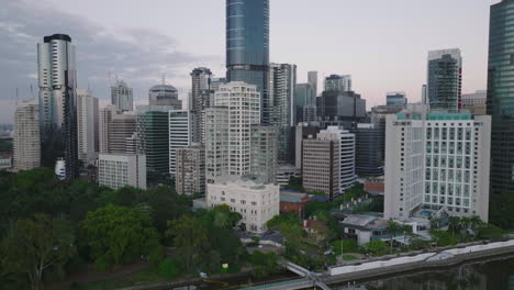 Filmdrohne,-Die-Bei-Sonnenaufgang-An-Der-Stadt-Und-Den-Gärten-Von-Brisbane-Vorbeifliegt