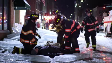 emergency responders work diligently on a cold urban street covered in ice. firefighters provide medical assistance to a person lying down, showcasing teamwork during a challenging situation.